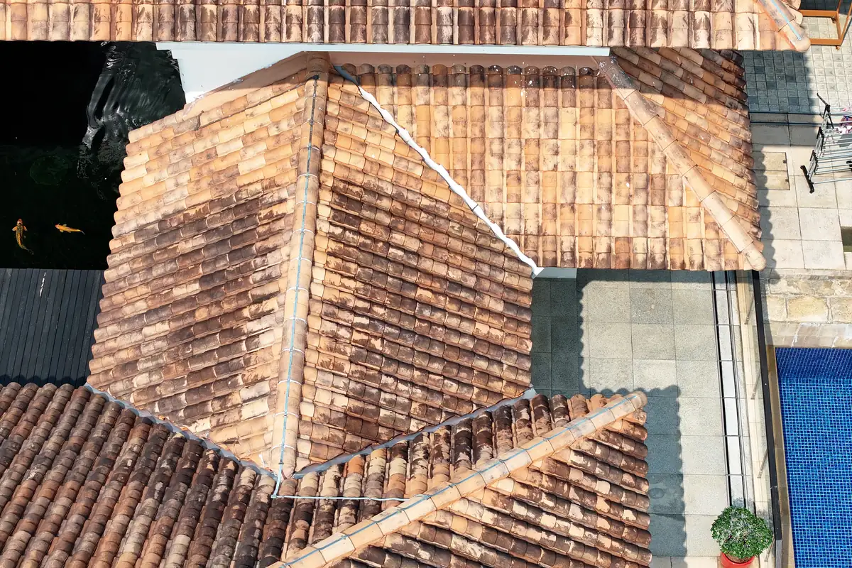 Roof-level drone view showing tiled roof planes, hip junctions and valley gutters in Singapore